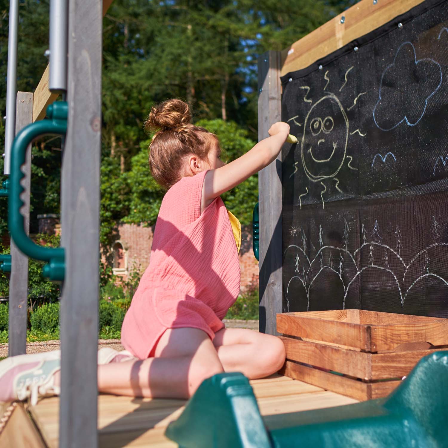 Girl drawing in the chalkboard in Plum Play's Siamang Wooden Playcentre Climbing Frame