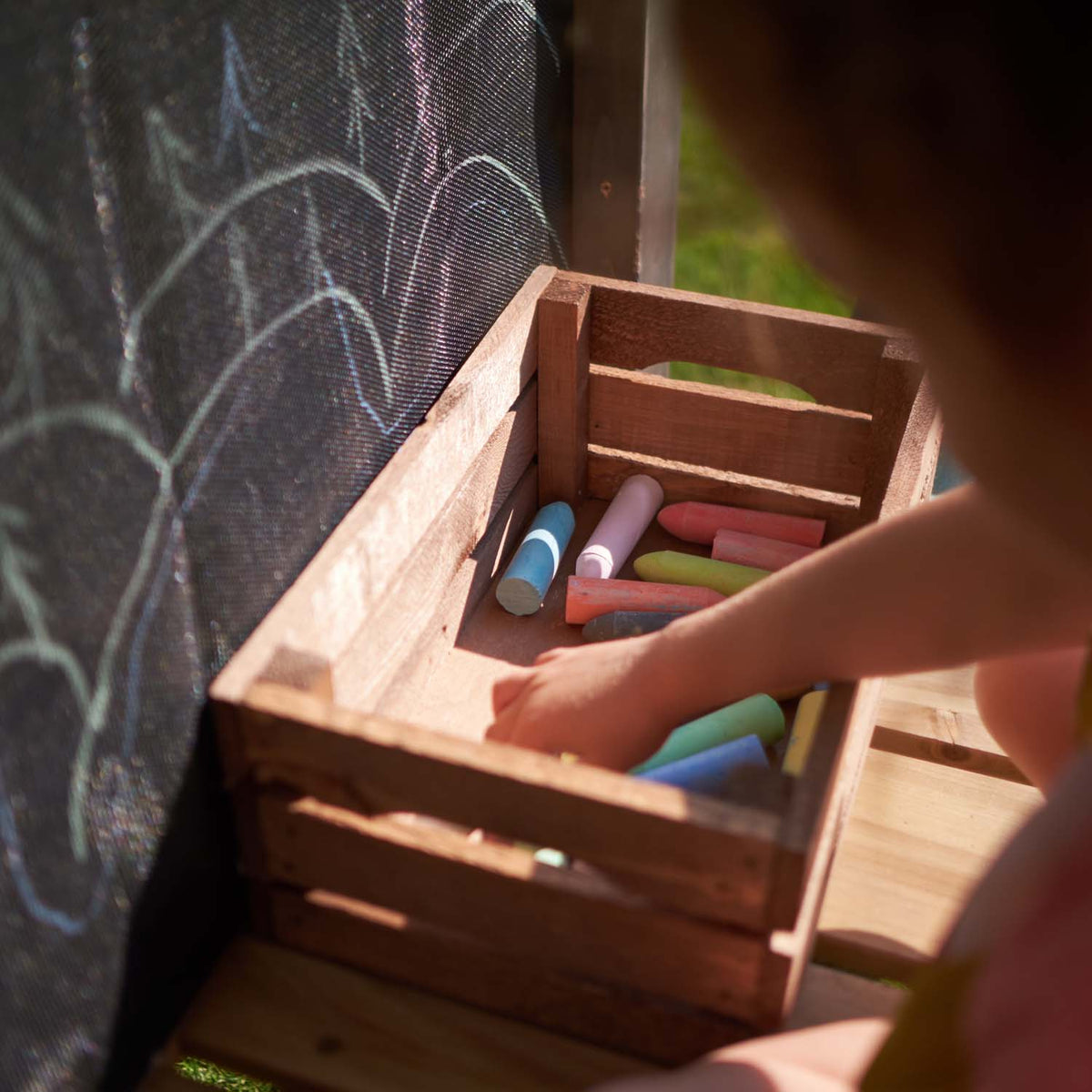 Child selecting a chalk in the wooden box in Plum Play's Siamang Wooden Playcentre