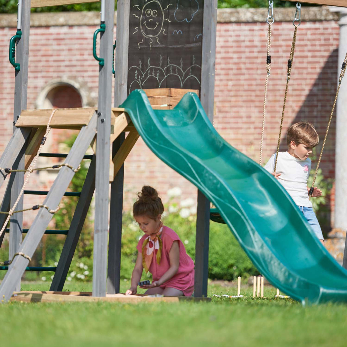 Two children playing in Plum Play's Siamang Wooden Playcentre Climbing Frame