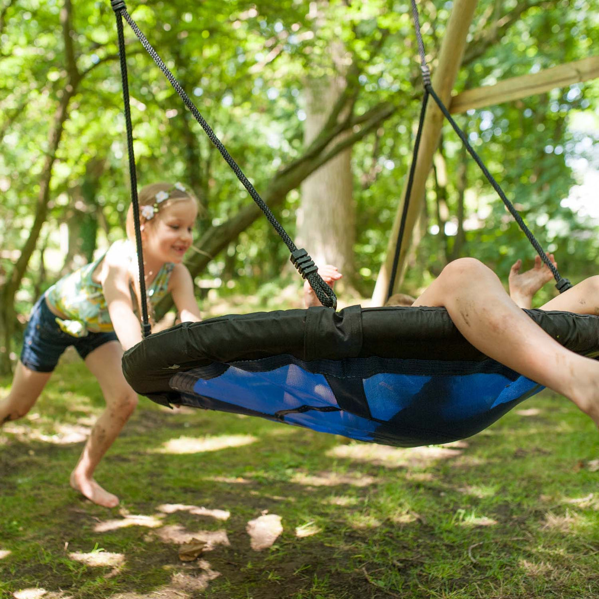 Children playing on the Plum Play's Spider Monkey Wooden Nest Swing Set