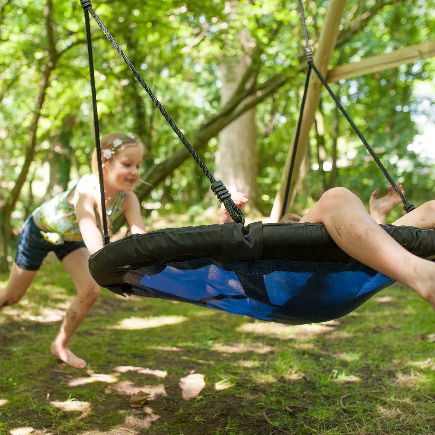 Children playing on the Plum Play's Spider Monkey Wooden Nest Swing Set