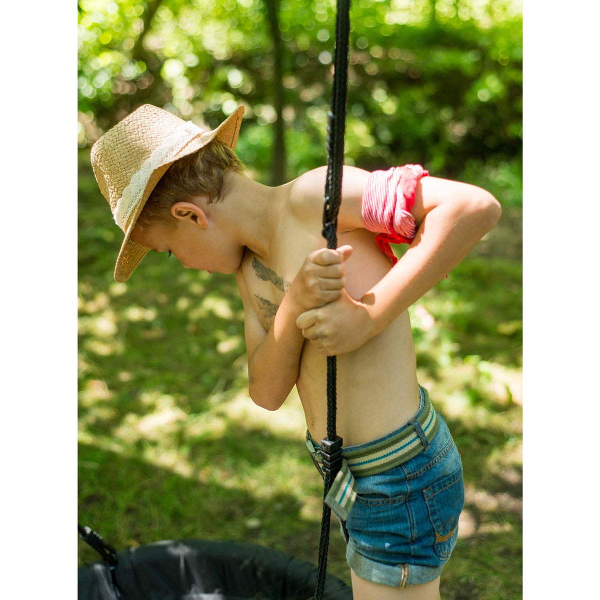 Boy holding the swing rope of Plum Play's Spider Monkey Wooden Nest Swing Set