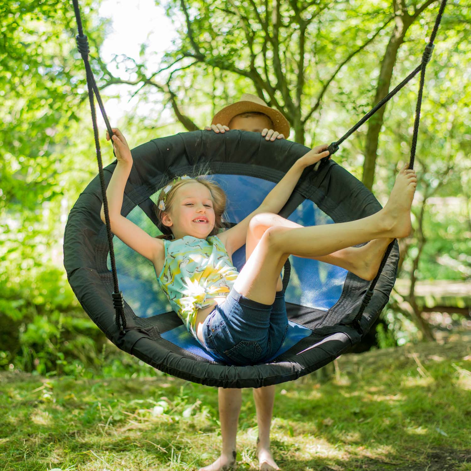 Children playing on Plum Play's Spider Monkey Wooden Nest Swing Set