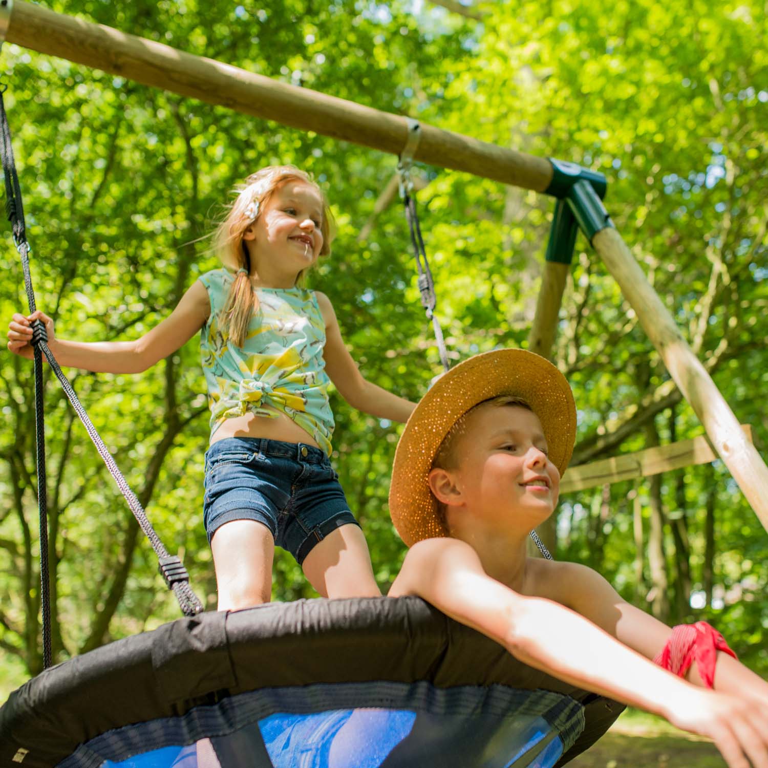 Children having fun playing on Plum Play's Spider Monkey Wooden Nest Swing Set