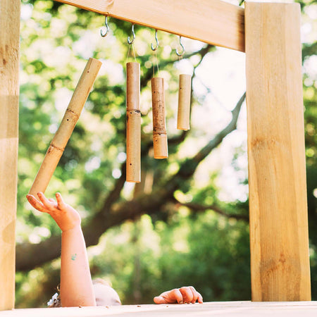 Child playing with the bamboo chimes in Plum Discovery Woodland Treehouse