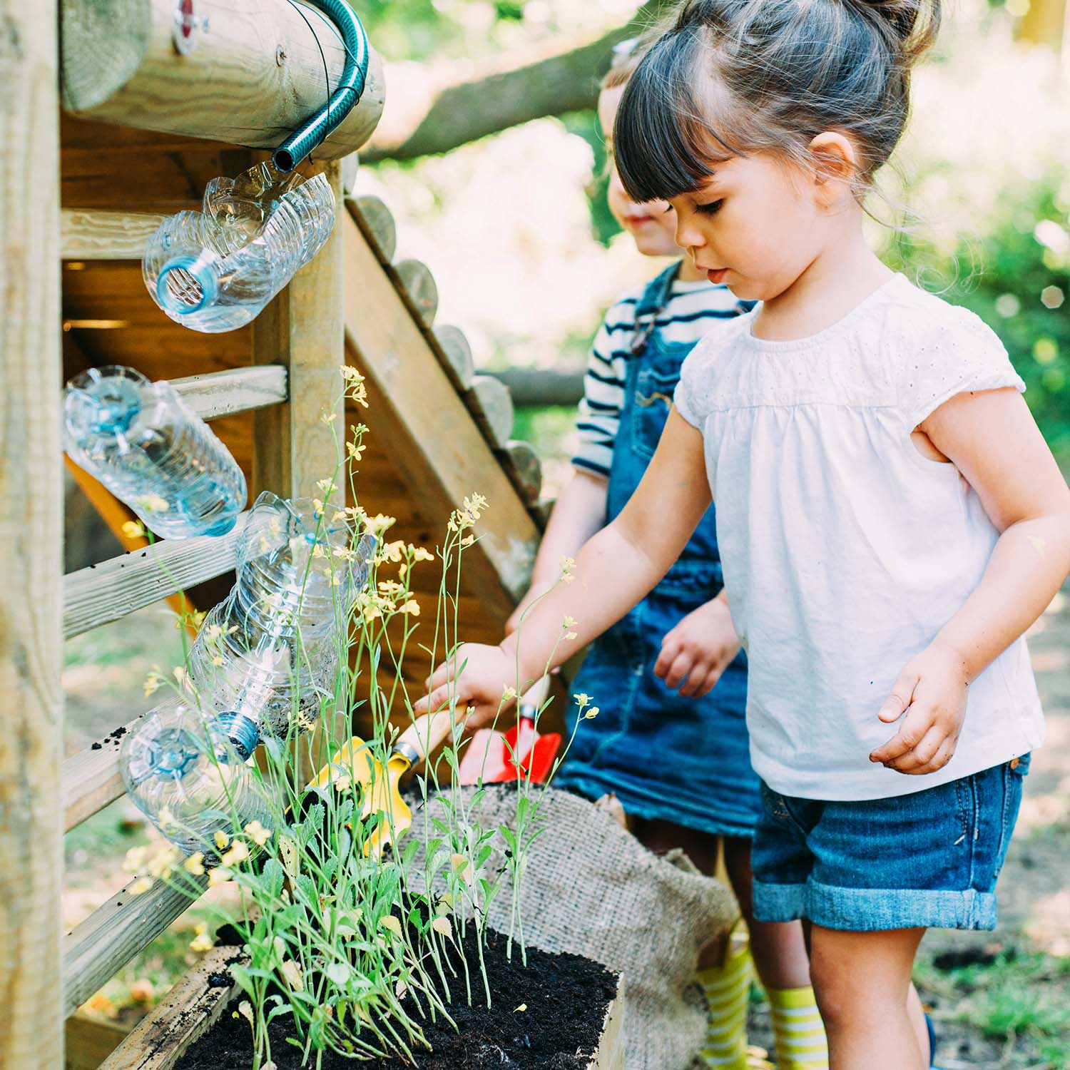 Children digging the soil of potted garden in Plum Play's Discovery Woodland Treehouse