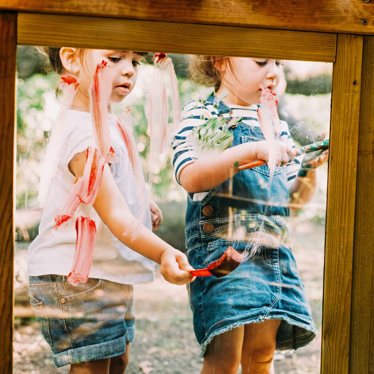 Children creating art in the painting screen of Plum Play's Discovery Woodland Treehouse