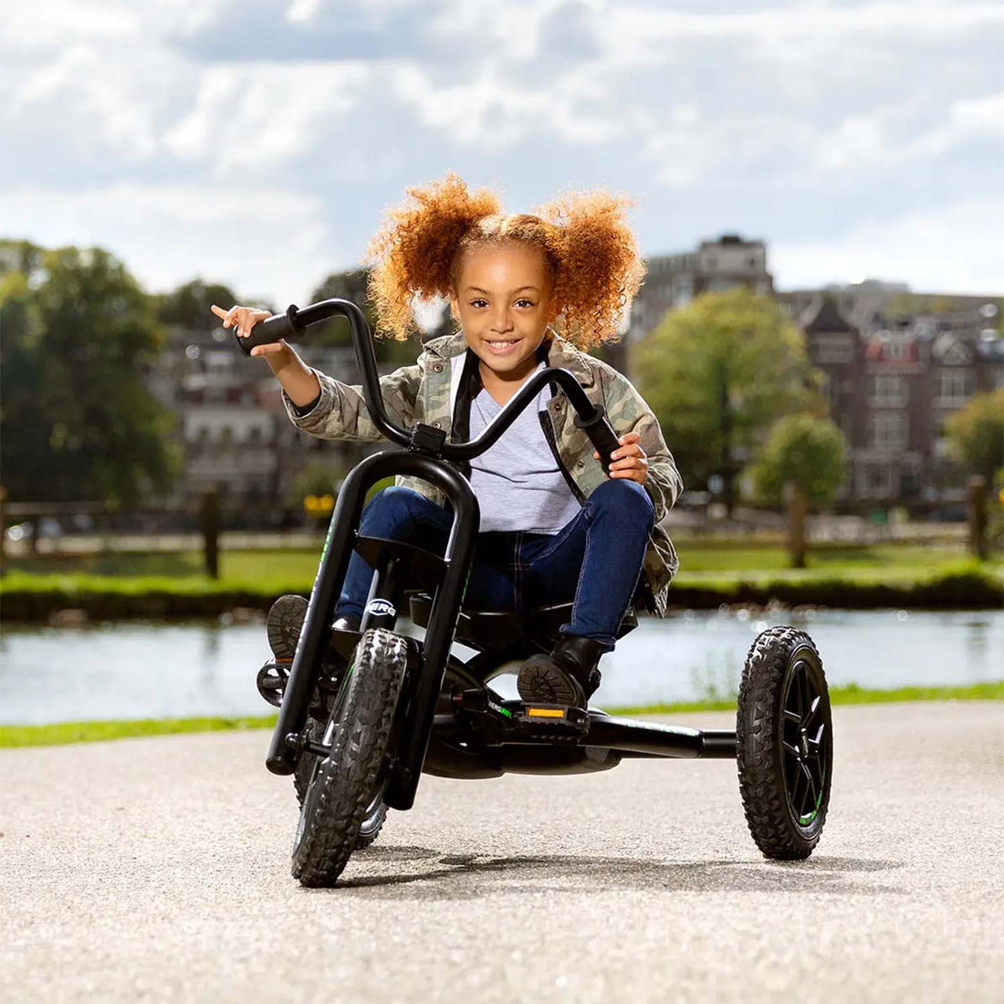 A young girl smiling while riding a BERG Buddy Choppy Neo Pedal Go-Kart