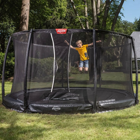 a boy wearing yellow shirt playing in BERG Elite InGround Round Trampoline with Safety Net Deluxe