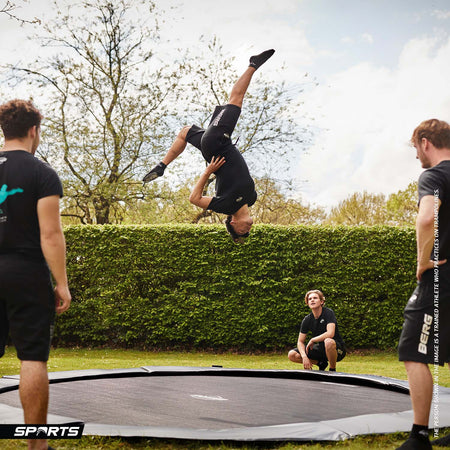 trained athletes practicing acrobatic routines in the BERG SPORTS Elite FlatGround Round Trampoline