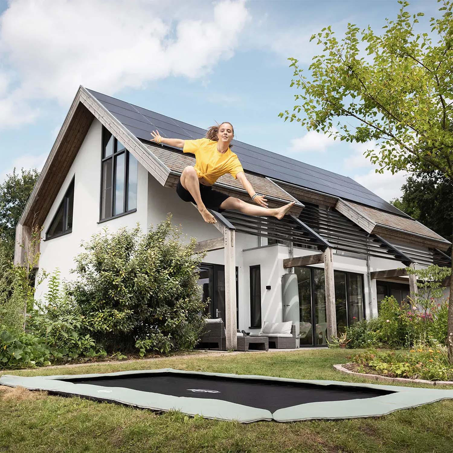 a trained athlete jumping on a BERG SPORTS Ultim Champion ECO FlatGround Rectangular Trampoline in Green colour