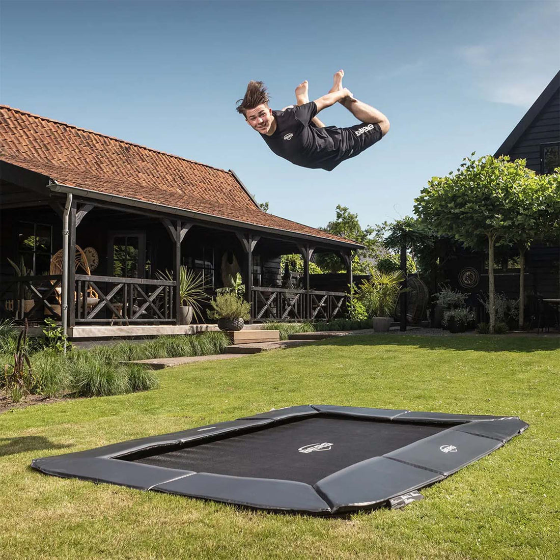 trained athlete performing acrobatics while boucing on a BERG SPORTS Ultim Champion FlatGround Rectangular Trampoline