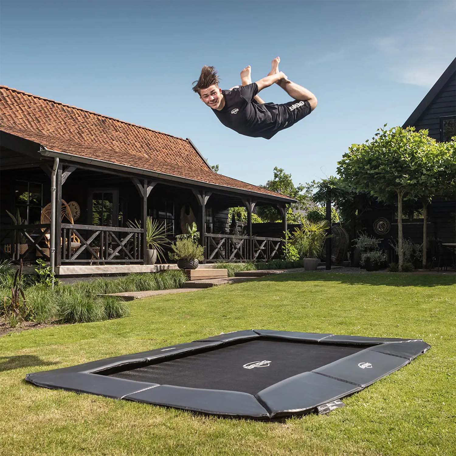 trained athlete performing acrobatics while boucing on a BERG SPORTS Ultim Champion FlatGround Rectangular Trampoline