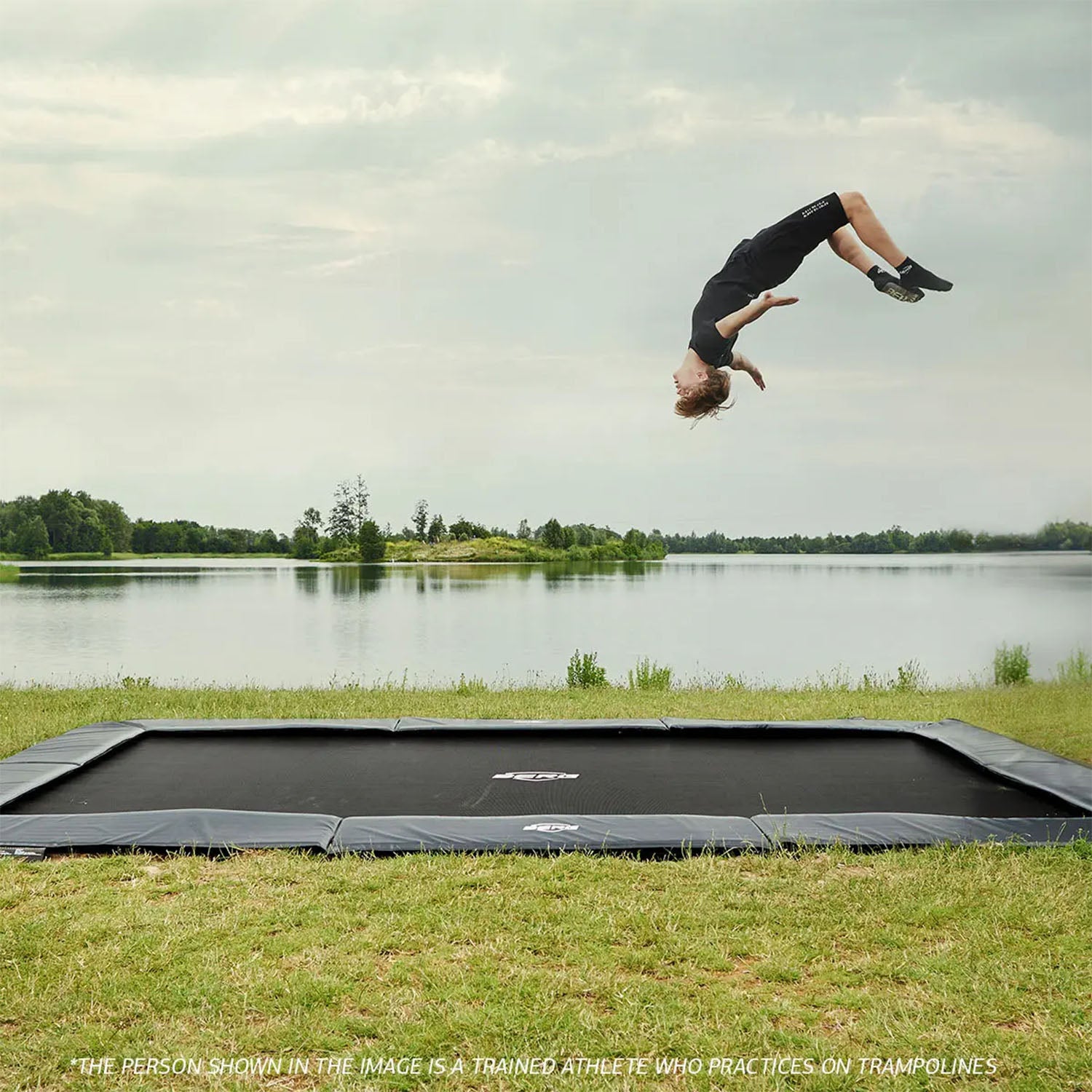 a trained athlete performing a somersault on a BERG SPORTS Ultim Elite FlatGround Rectangular Trampoline