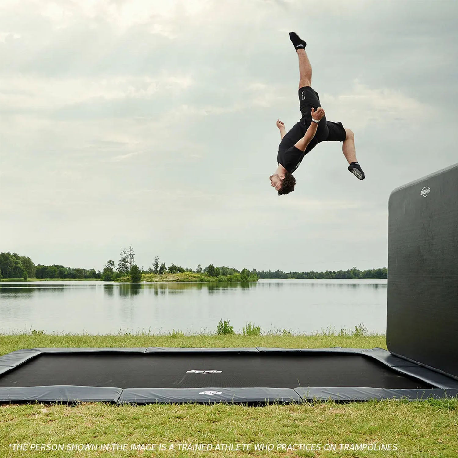 a trained athlete performing acrobatics on the BERG SPORTS Ultim Elite FlatGround Rectangular Trampoline with AeroWall