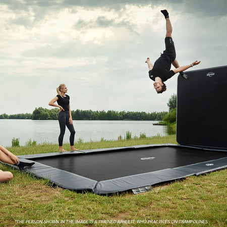 a trained athlete practicing a  somersault on the BERG SPORTS Ultim Elite FlatGround Rectangular Trampoline with AeroWall 